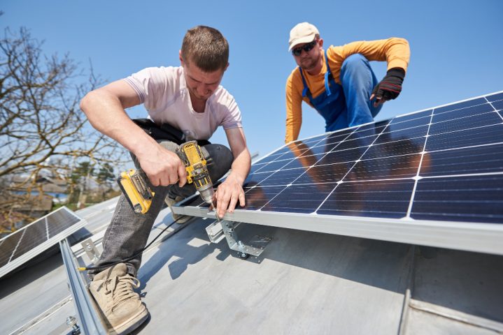 deux ouvriers qui installent un panneau solaire sur un toit