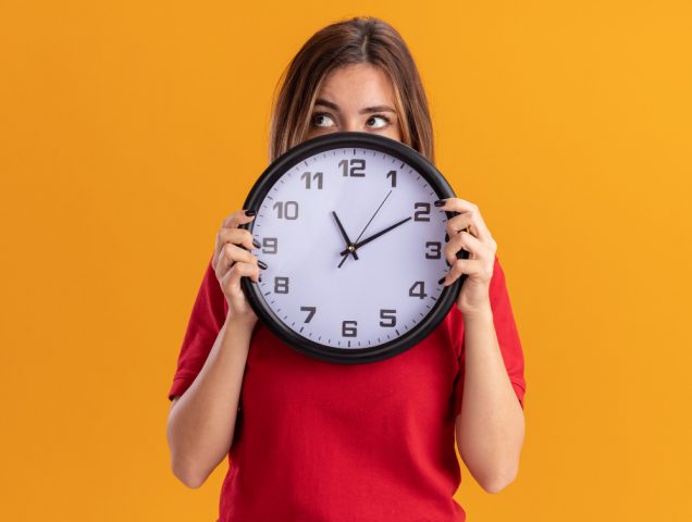 une femme tient une grande horloge sur un fond jaune